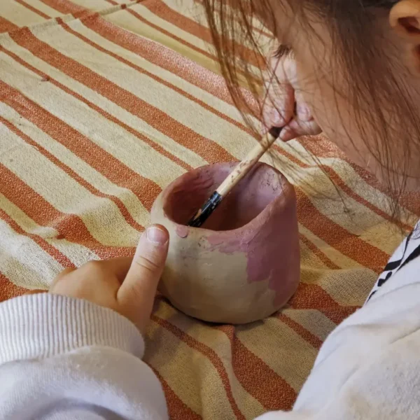 çocuk seramik kusru istanbul Fluu Studio çocuk seramik kursunda el yapımı çamur kupasını pembe boya ile renklendiren çocuk